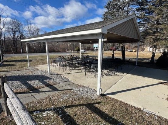 A covered area with tables and chairs under a roof.