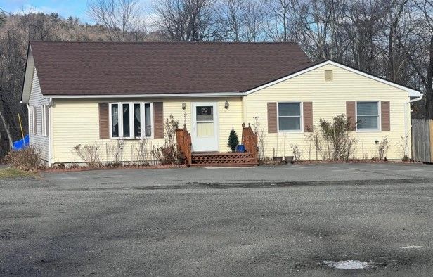 A large yellow house with a brown roof is sitting in a parking lot.