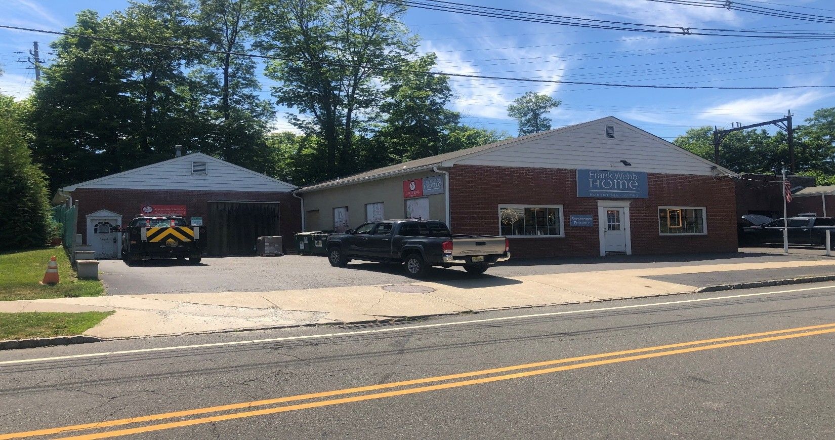 Small roadside brick building with a black garage and a pickup truck parked in front under a blue sky.
