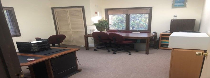 Office with desks, chairs, window, television, and door.