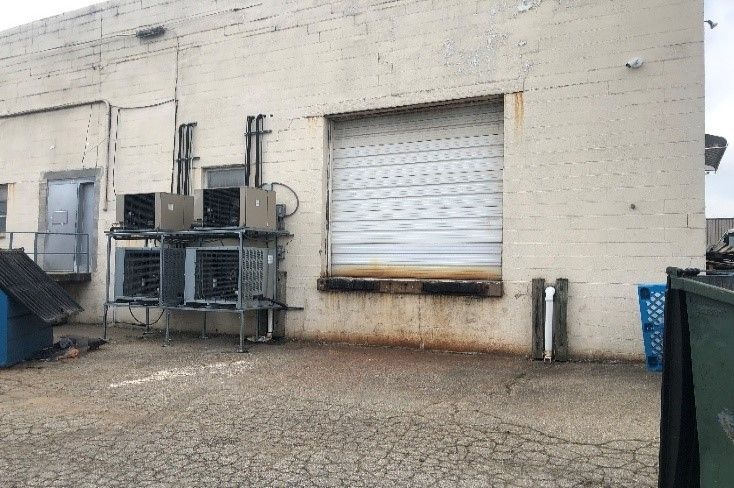 The back of a building with a warehouse door and a loading dock.