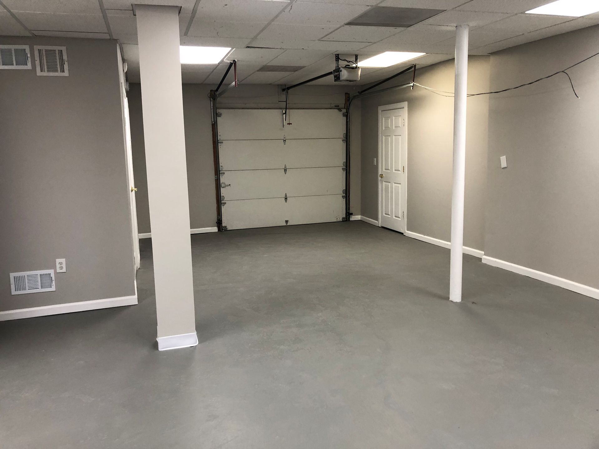Empty room with a garage door and gray walls and floor.