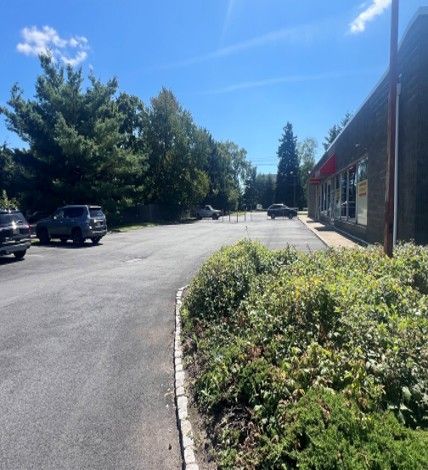 Small strip mall with red awnings and a parking lot on a sunny day