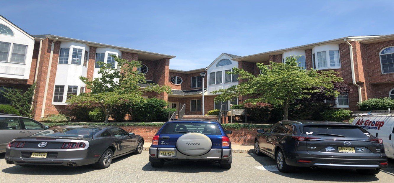 Cars parked in front of a brick building with white trim, under a clear blue sky.