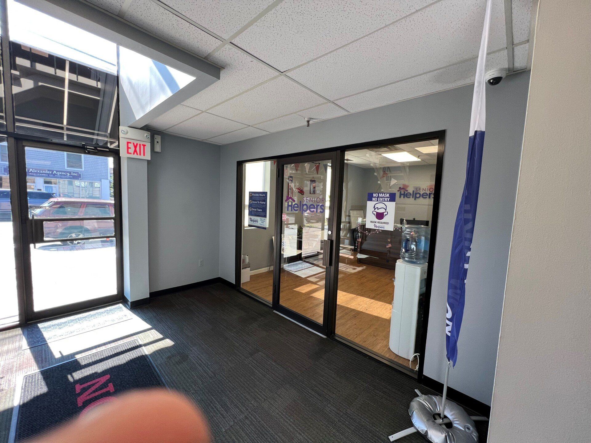Entrance to an office with glass doors, a water cooler, and a flag.
