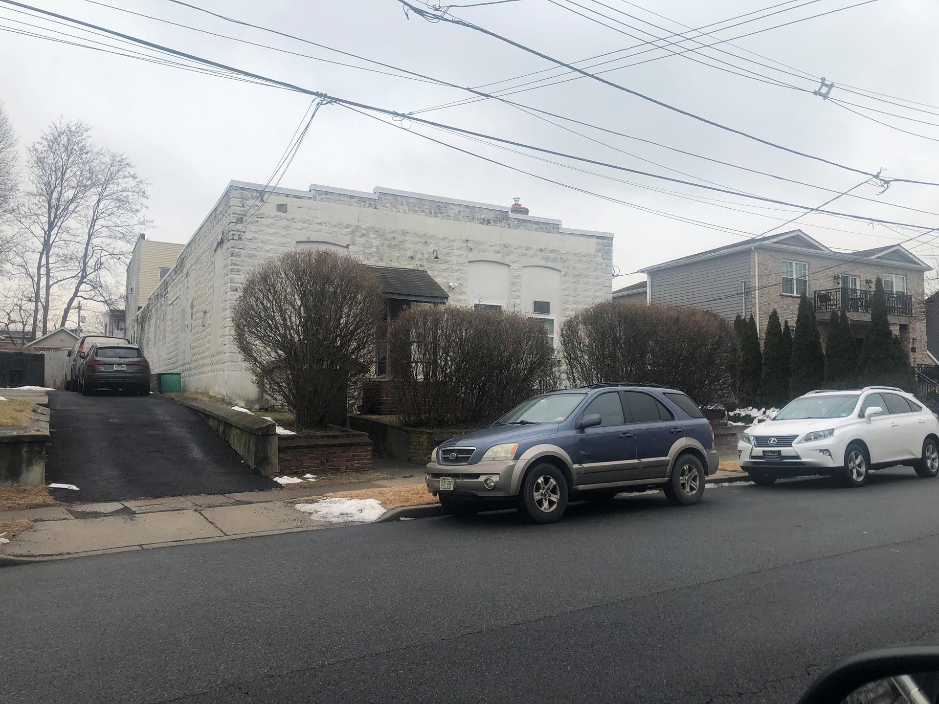 Two cars are parked on the side of the road in front of a house.