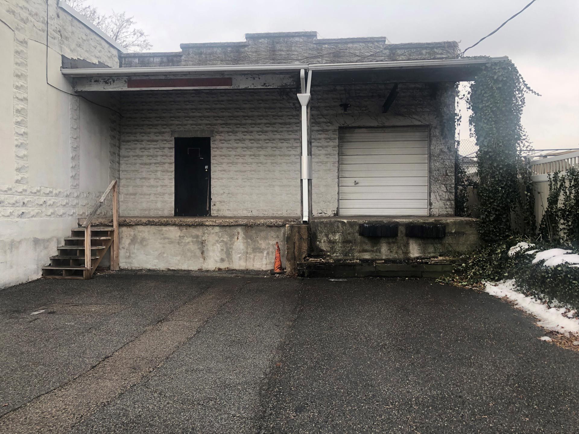The back of a building with a garage door and stairs.