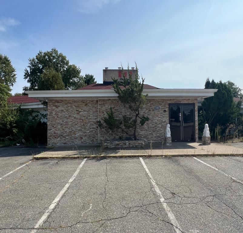 A brick building with a red roof sits in a parking lot