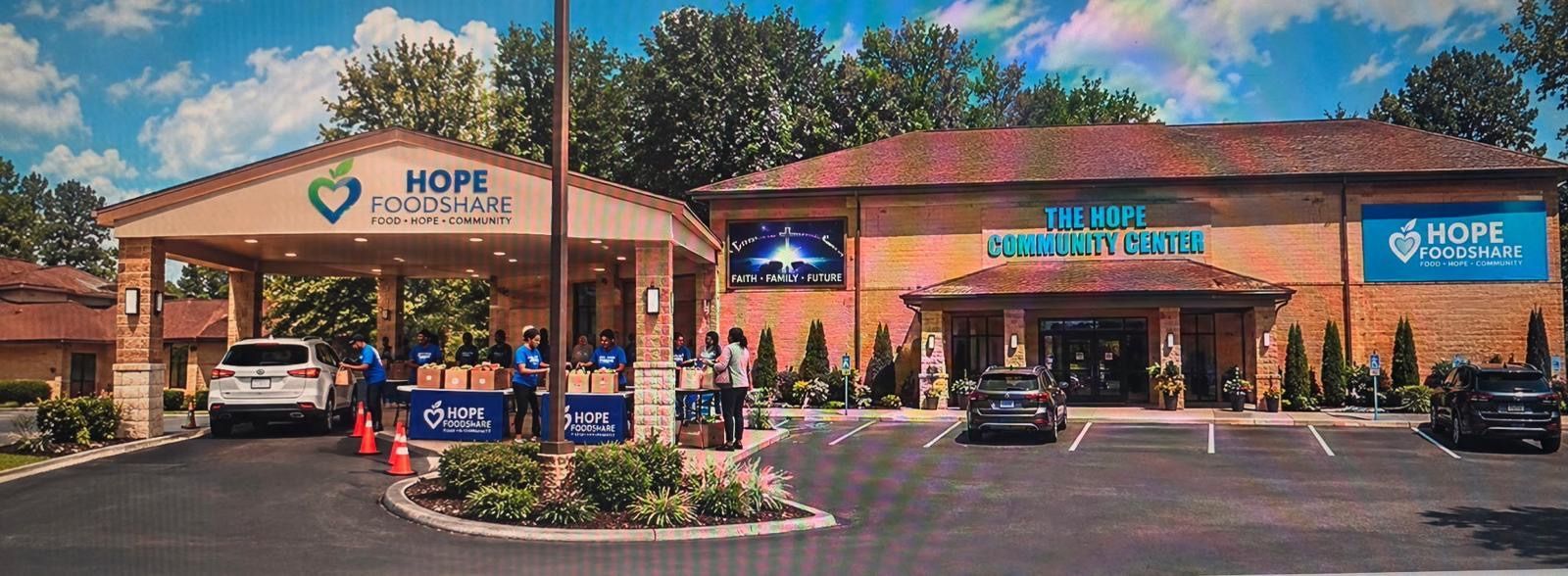 Conceptual rendering of the building entrance and covered drive-up area with volunteers at community food-service tables.
