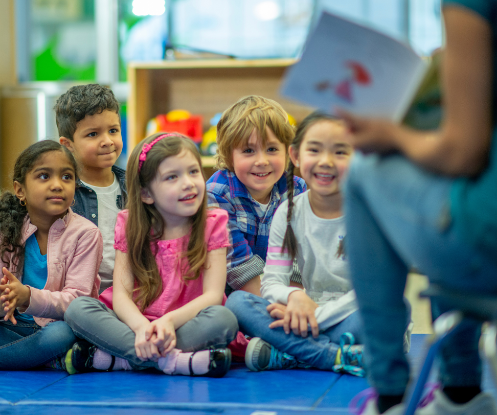 A group of children are sitting on the floor listening to a story.