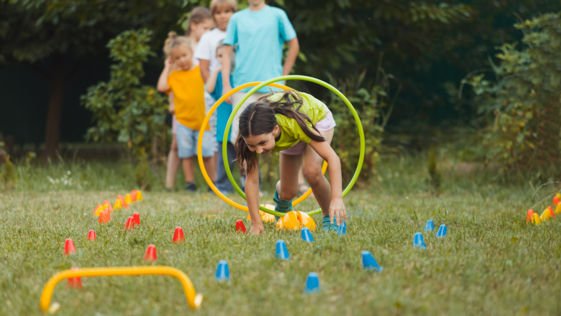 A group of children are playing with hula hoops in a park.