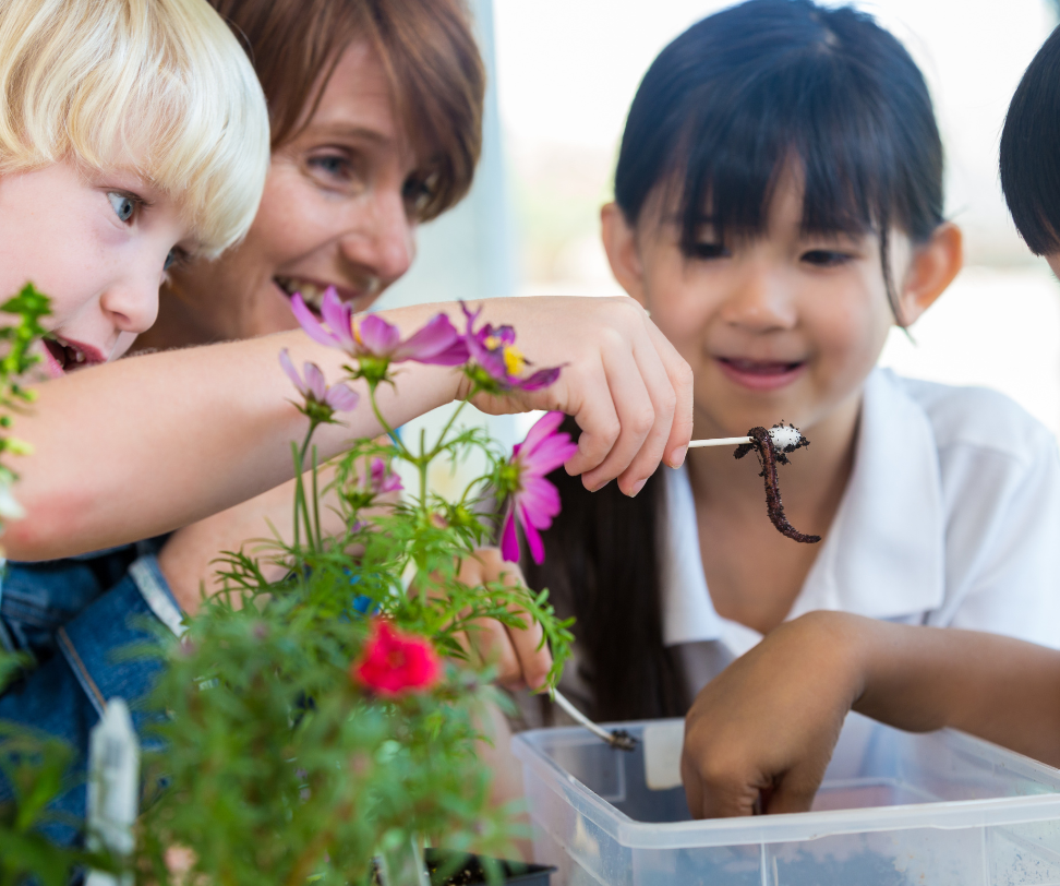 A group of children are looking at a worm in a plastic container