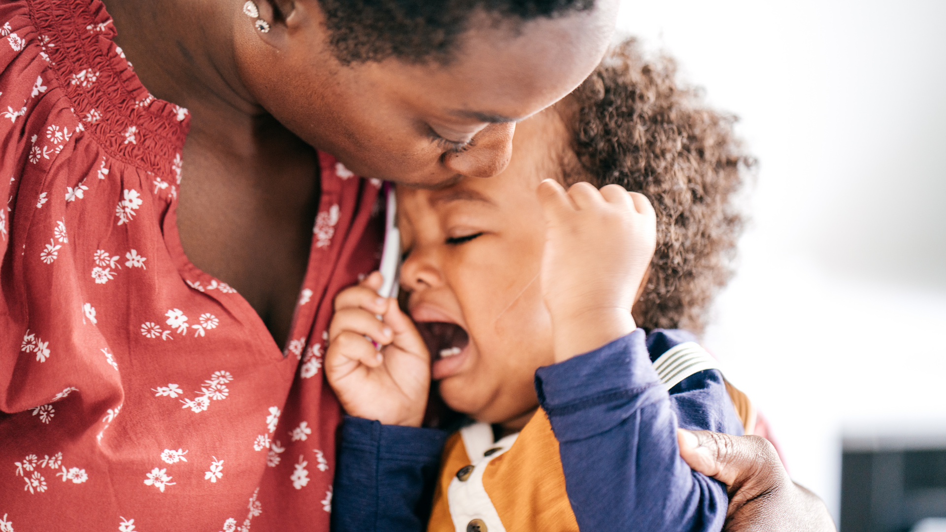 A woman is holding a crying baby in her arms.