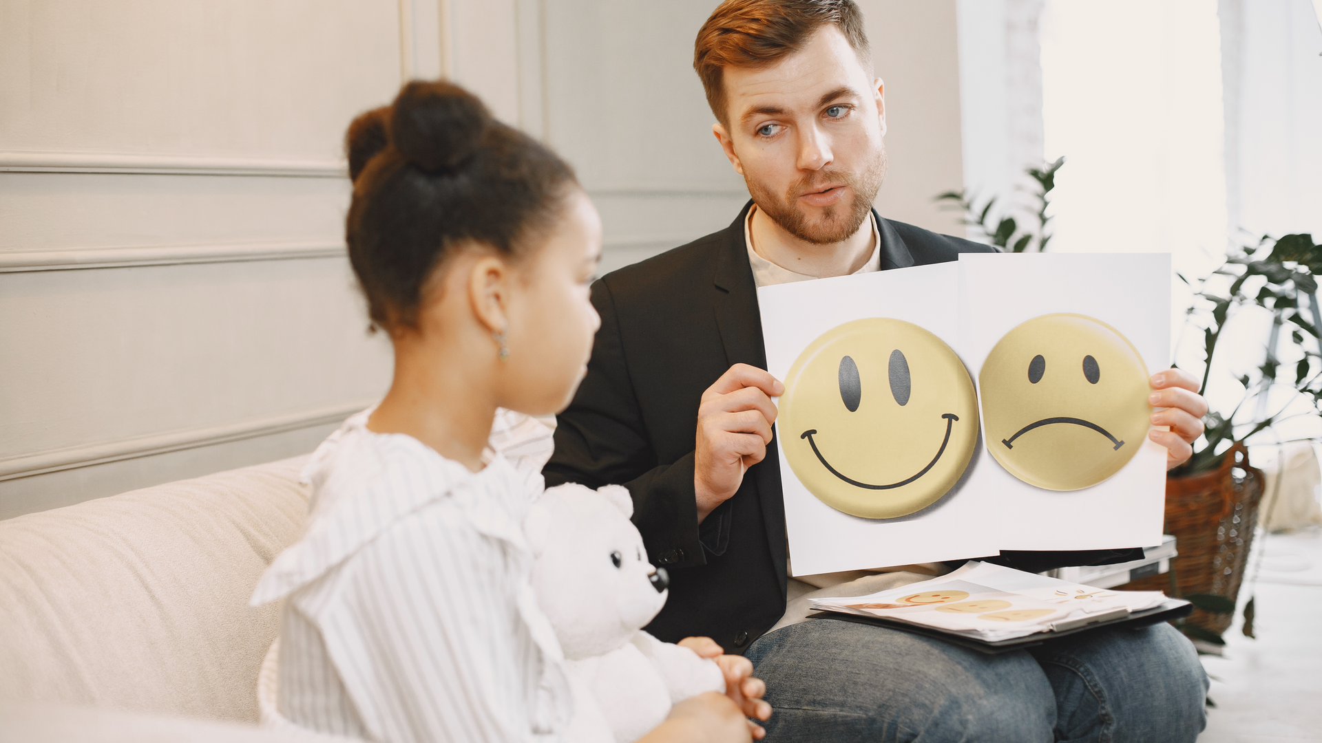 A man is holding a piece of paper with three smiley faces on it.