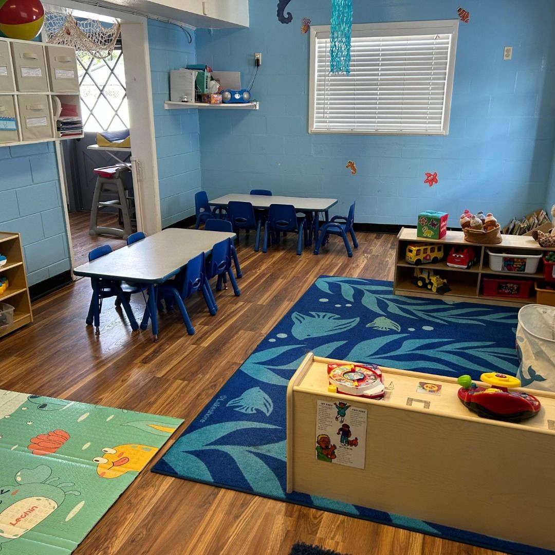 A classroom with tables and chairs and a blue rug.