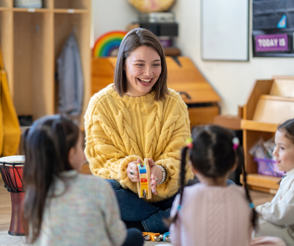 A woman is sitting on the floor playing with a group of children.