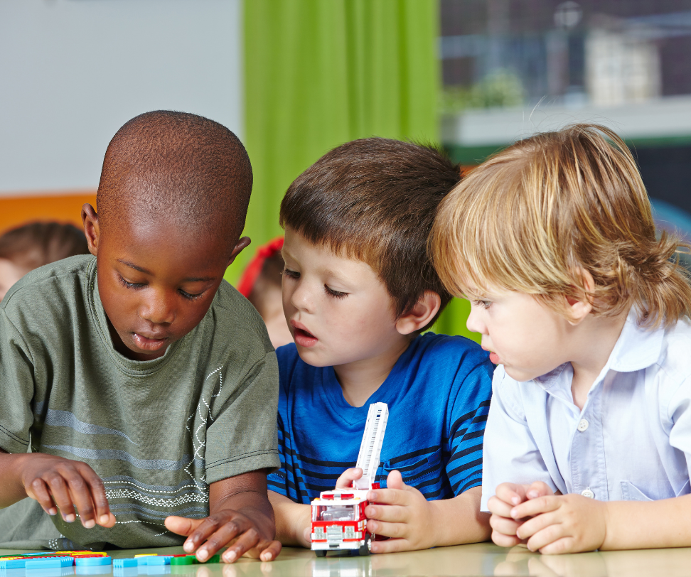 Three young boys are playing with a toy fire truck