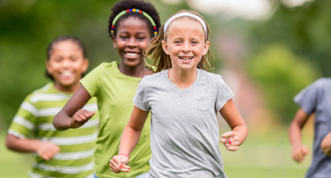 A group of young girls are running in a park.