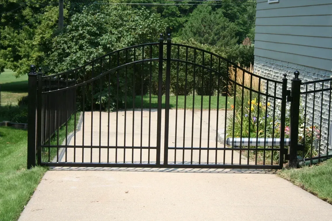a black wrought iron gate is open to a driveway