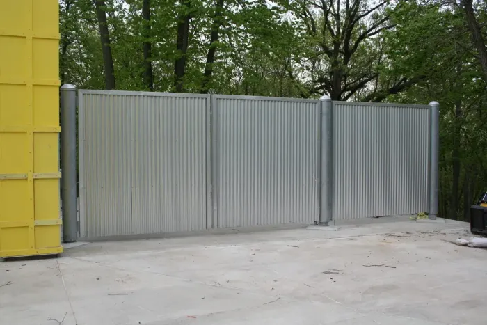 a gray fence with a yellow building in the background