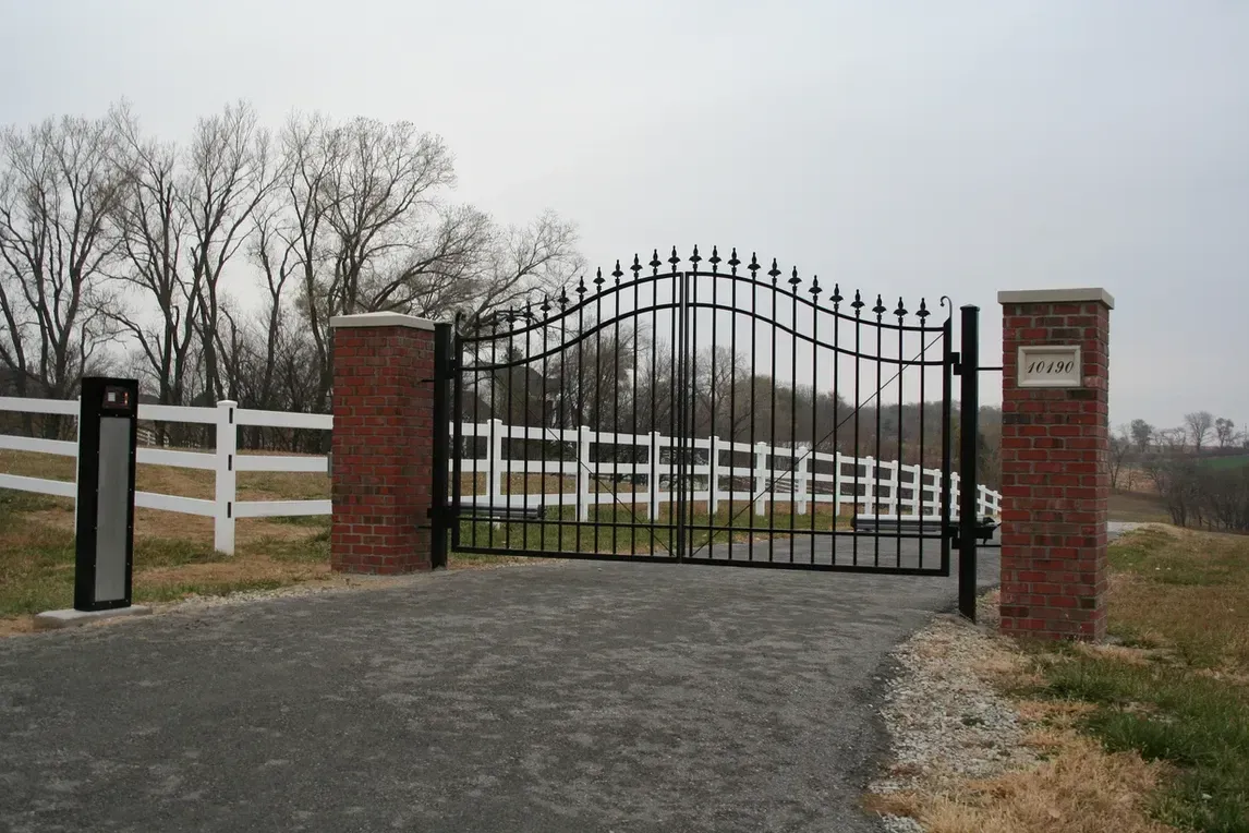 a black gate with a white fence behind it