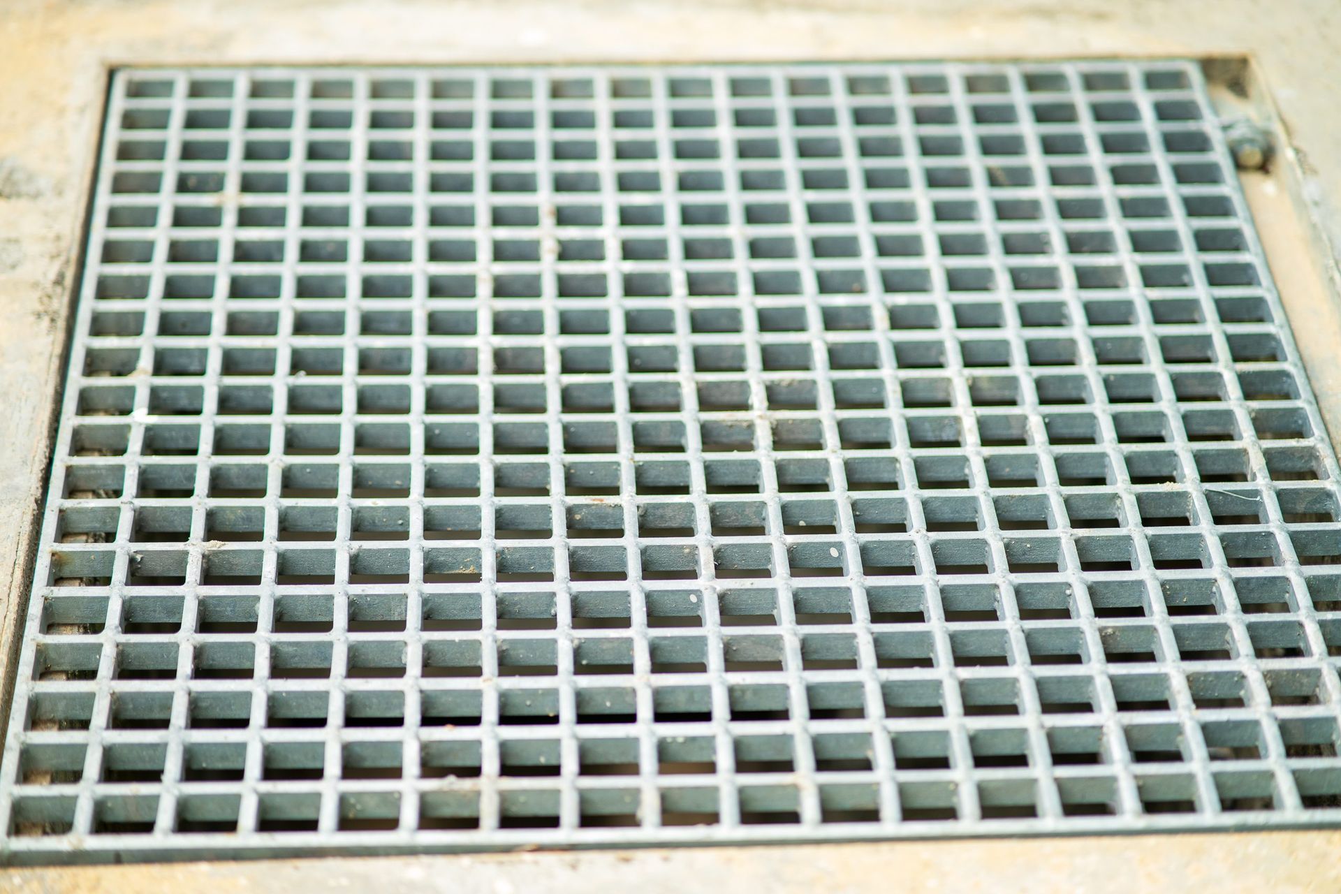 Square metal drain cover with a grid pattern.