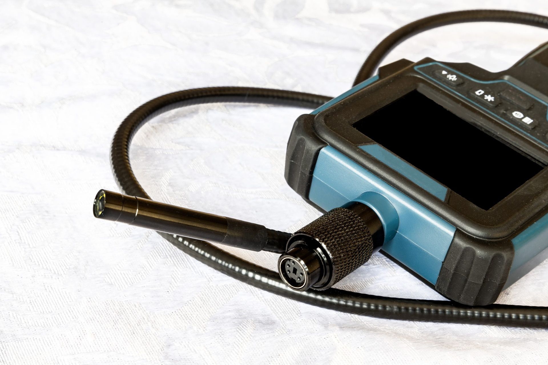 Endoscope with a black probe and blue and black handle on a white surface.