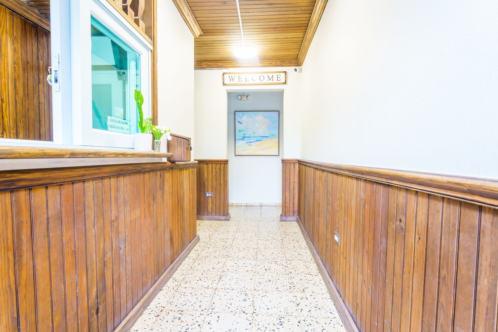 A long hallway with wooden walls and a painting on the wall.