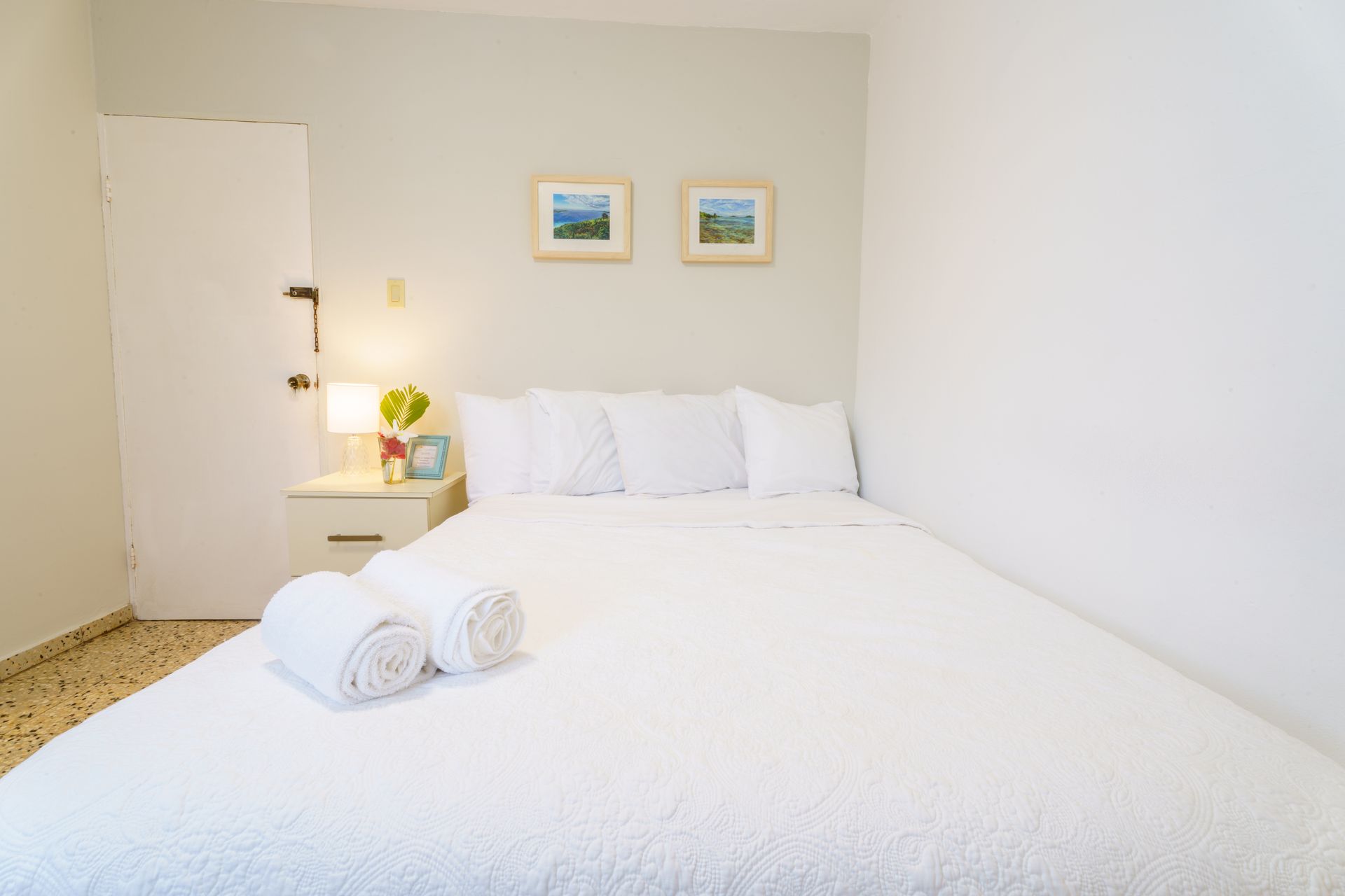 A bedroom with a bed , nightstand , and two towels on the bed.