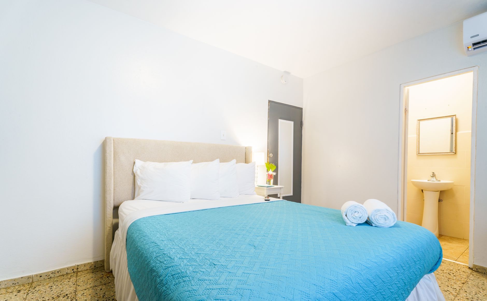 There is a bed with a blue blanket in the middle of the room.