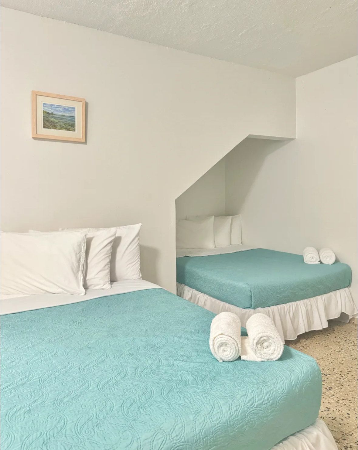 A hotel room with two beds and a picture on the wall