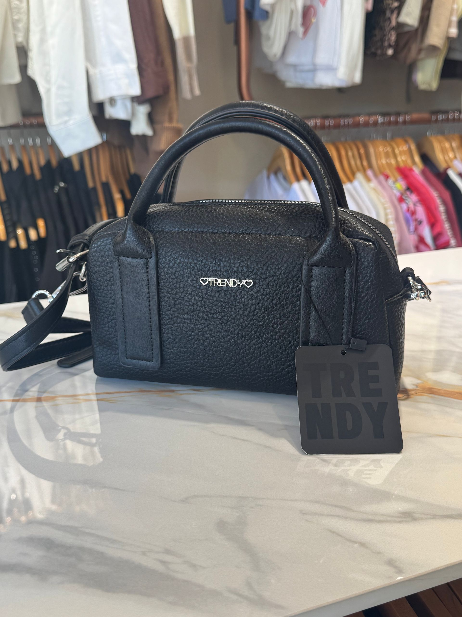 Bolso de mano negro texturizado con una etiqueta que dice 