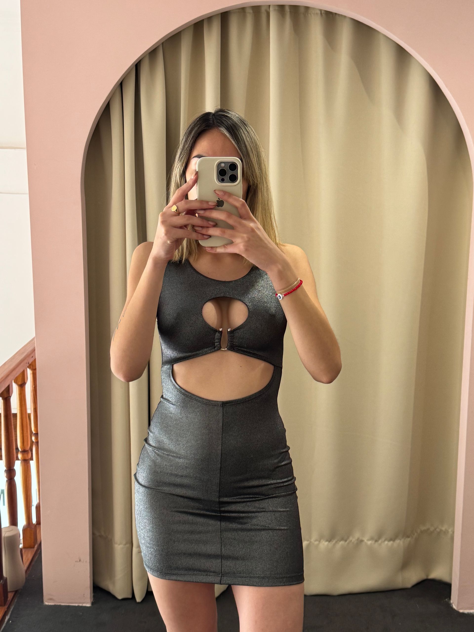 Mujer con un vestido plateado brillante tomándose una selfie frente al espejo.