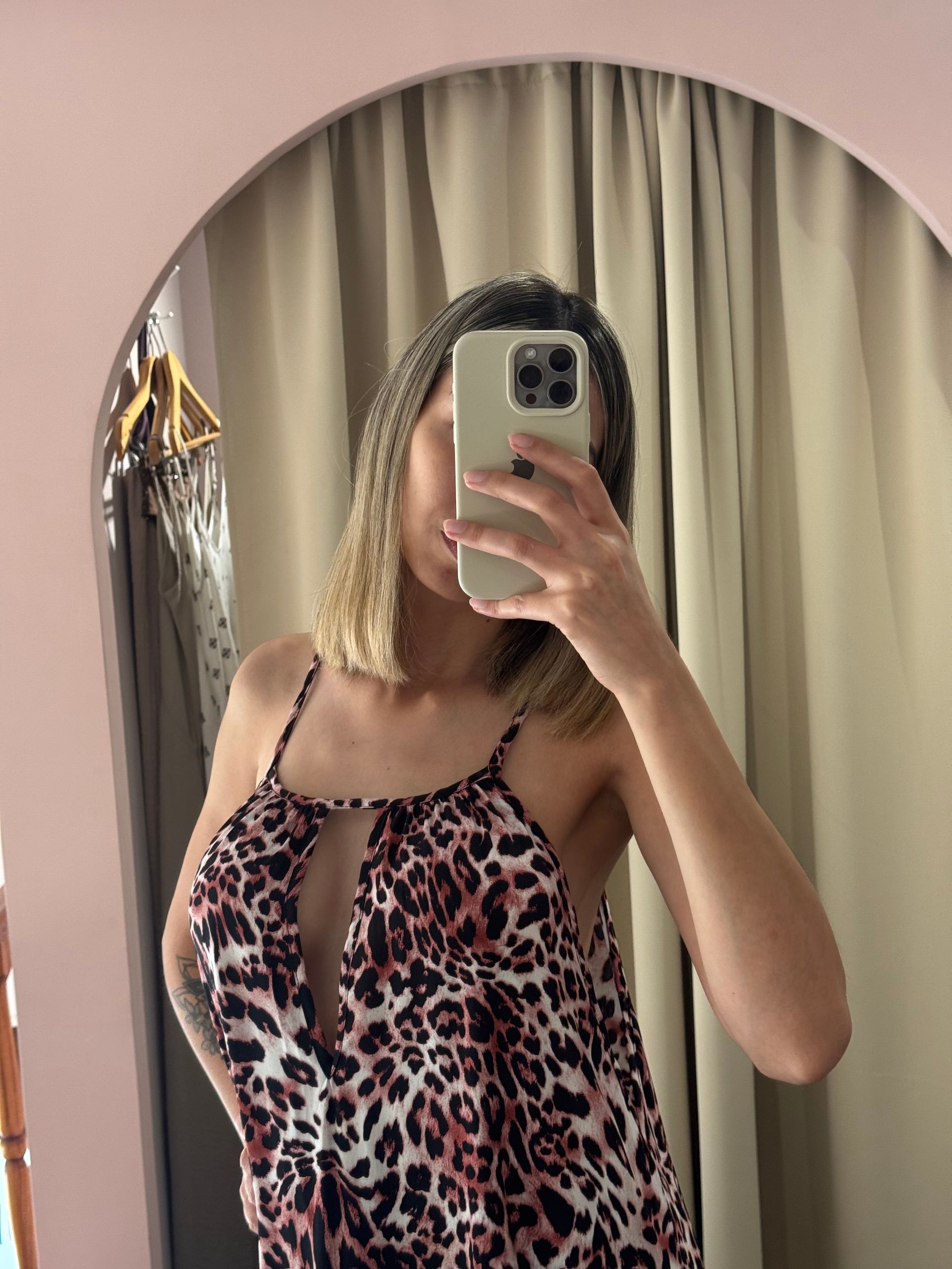 Mujer con vestido estampado de leopardo tomándose una selfie en el espejo.