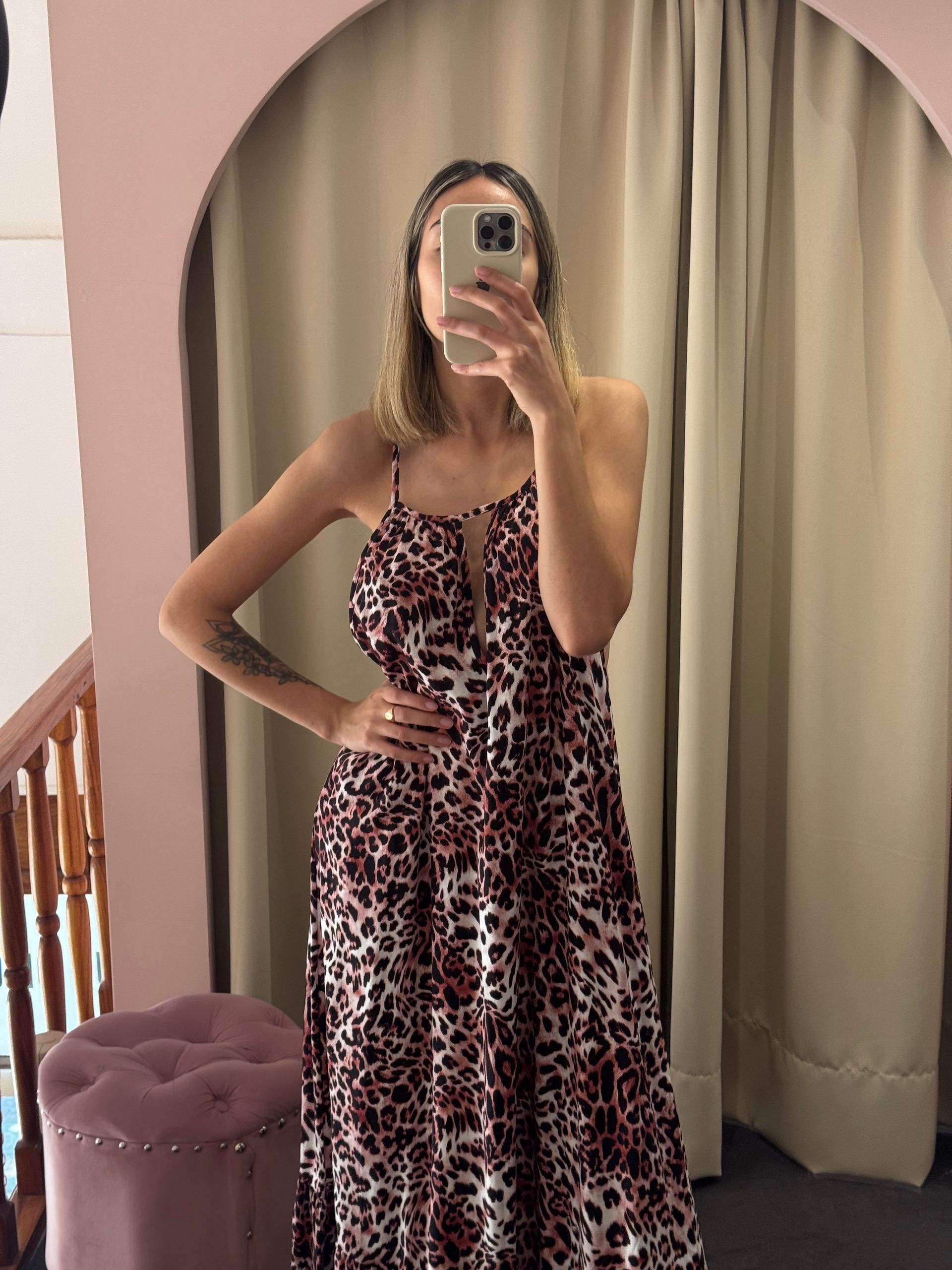 Mujer con vestido estampado de leopardo tomándose una selfie en el espejo.