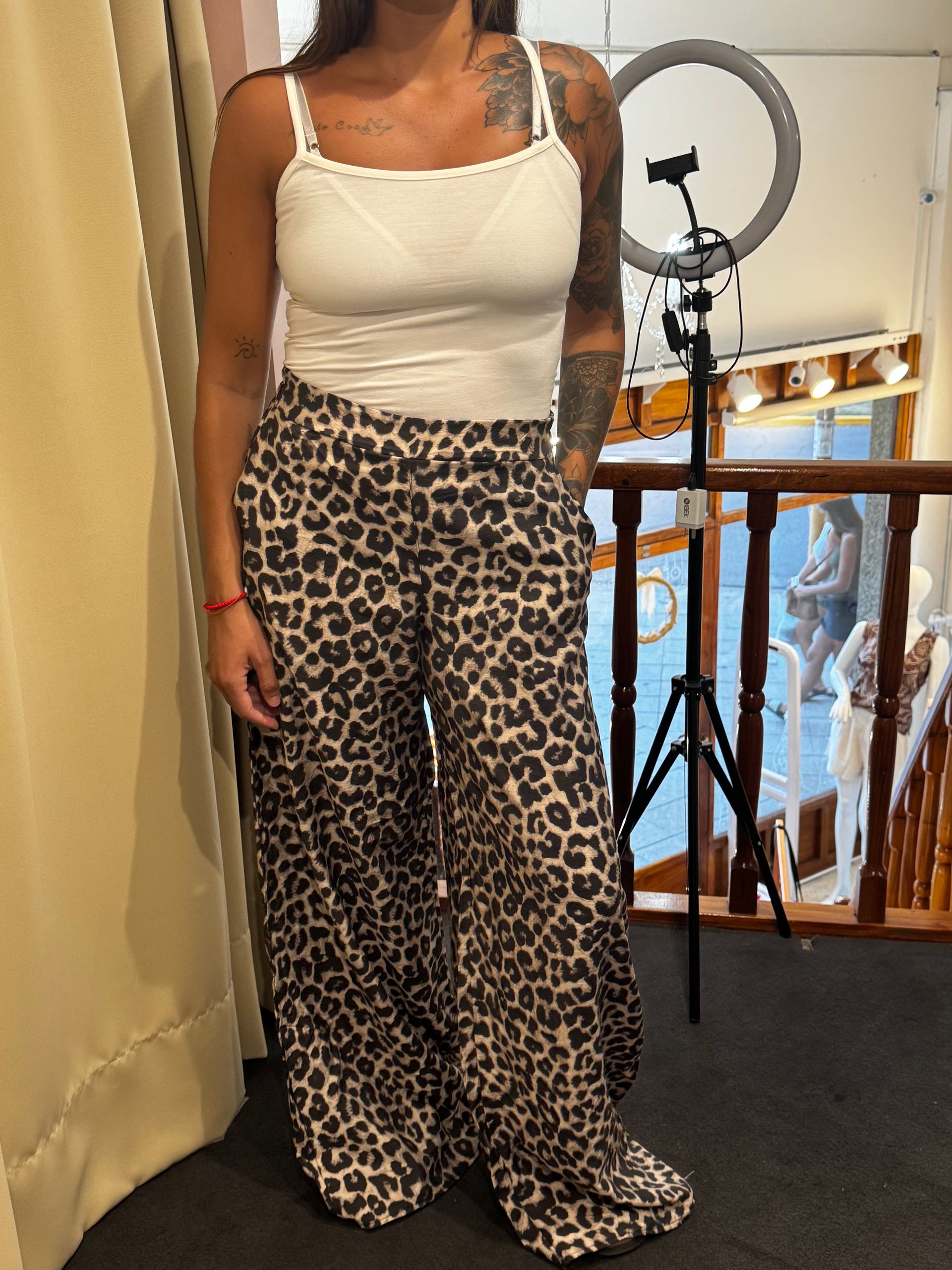 Una mujer con top blanco y pantalones con estampado de leopardo está parada en las escaleras.