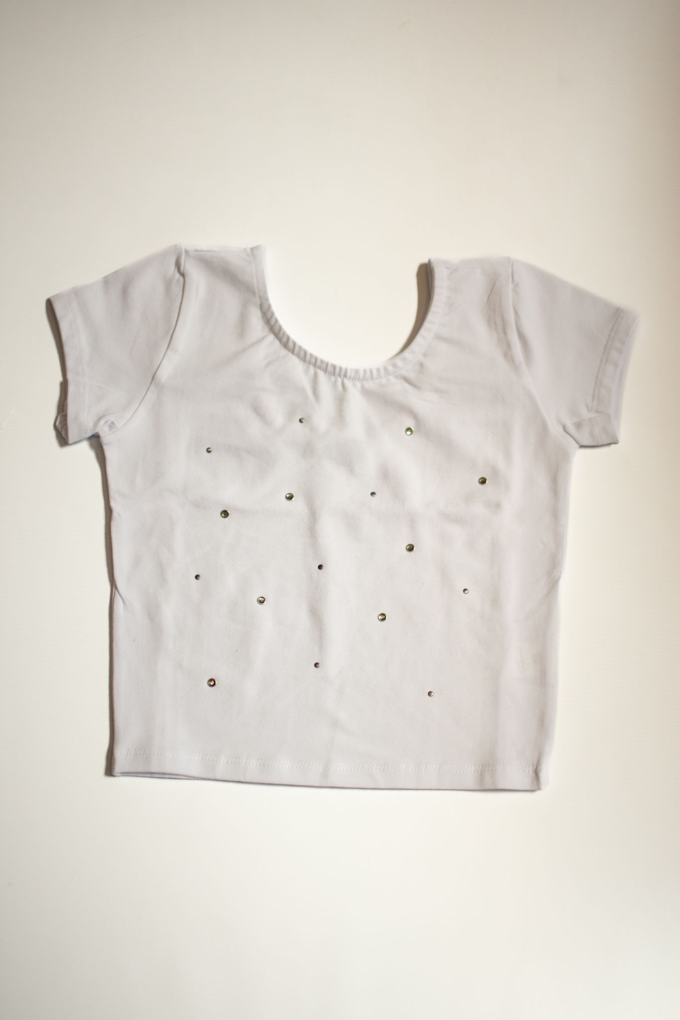 Blusa blanca de manga corta con escote redondo, pequeños agujeros, sobre fondo blanco.