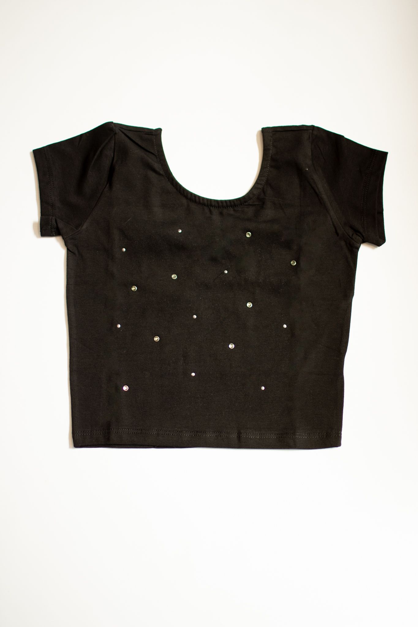 Blusa blanca de manga corta con escote redondo, pequeños agujeros, sobre fondo blanco.