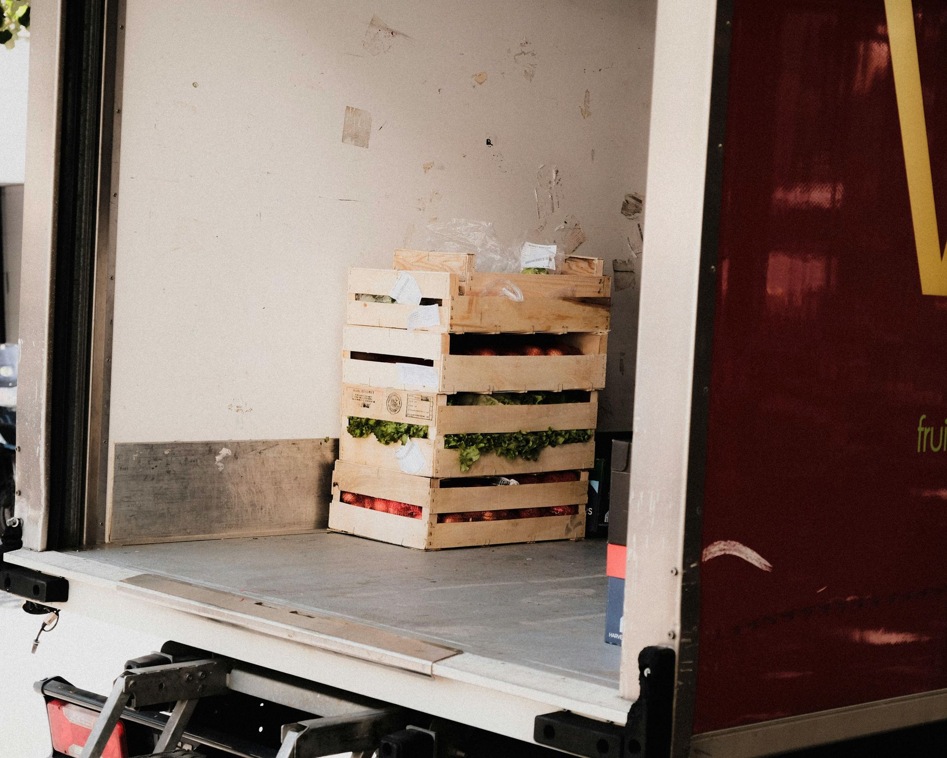 Stacked wooden crates in the back of a truck near an open loading door.