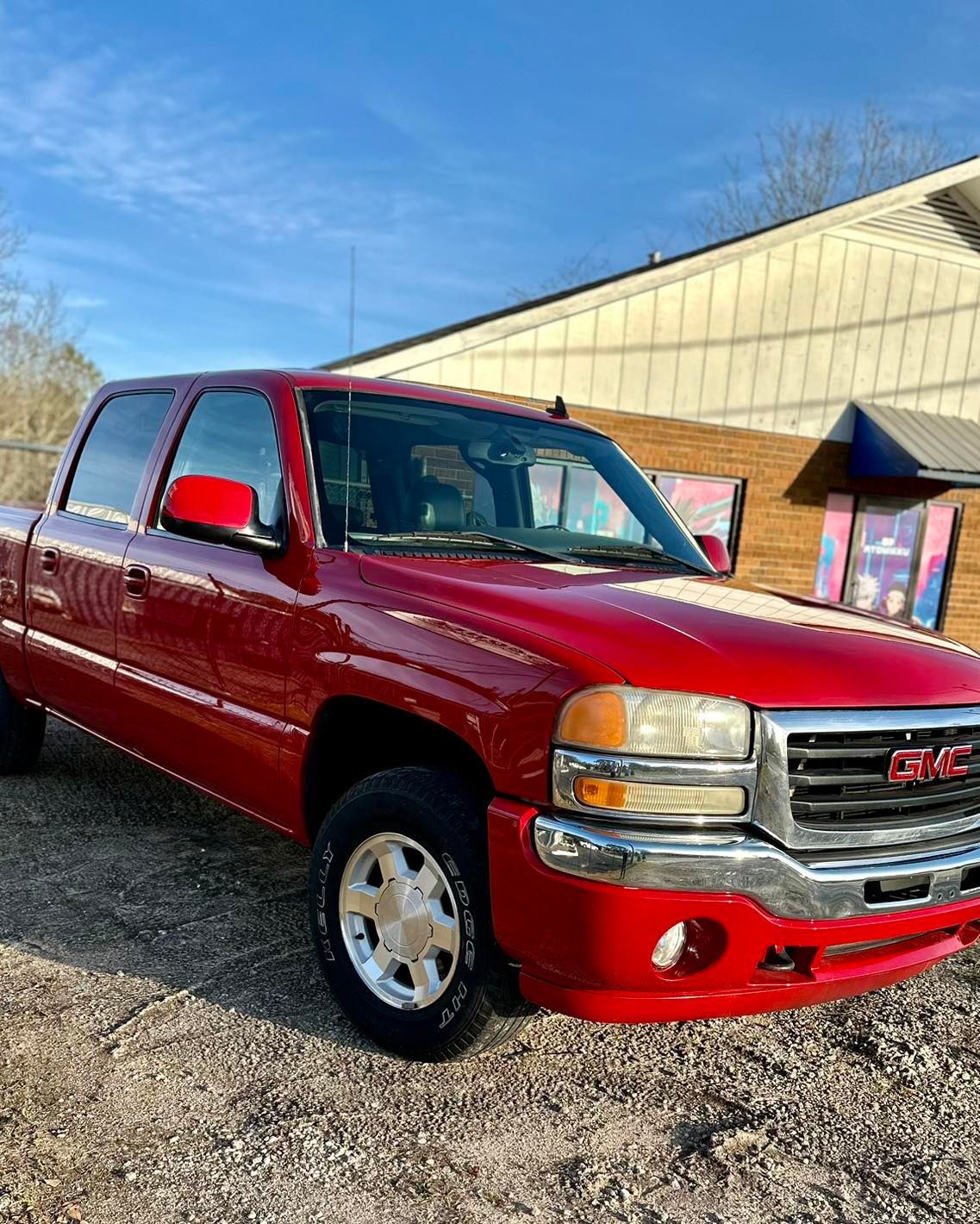 A red gmc truck is parked in front of a building.