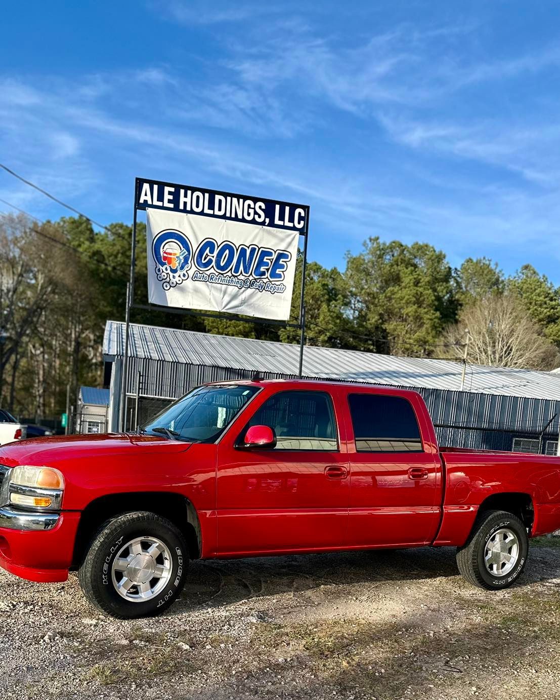 A red truck is parked in front of a car dealership.