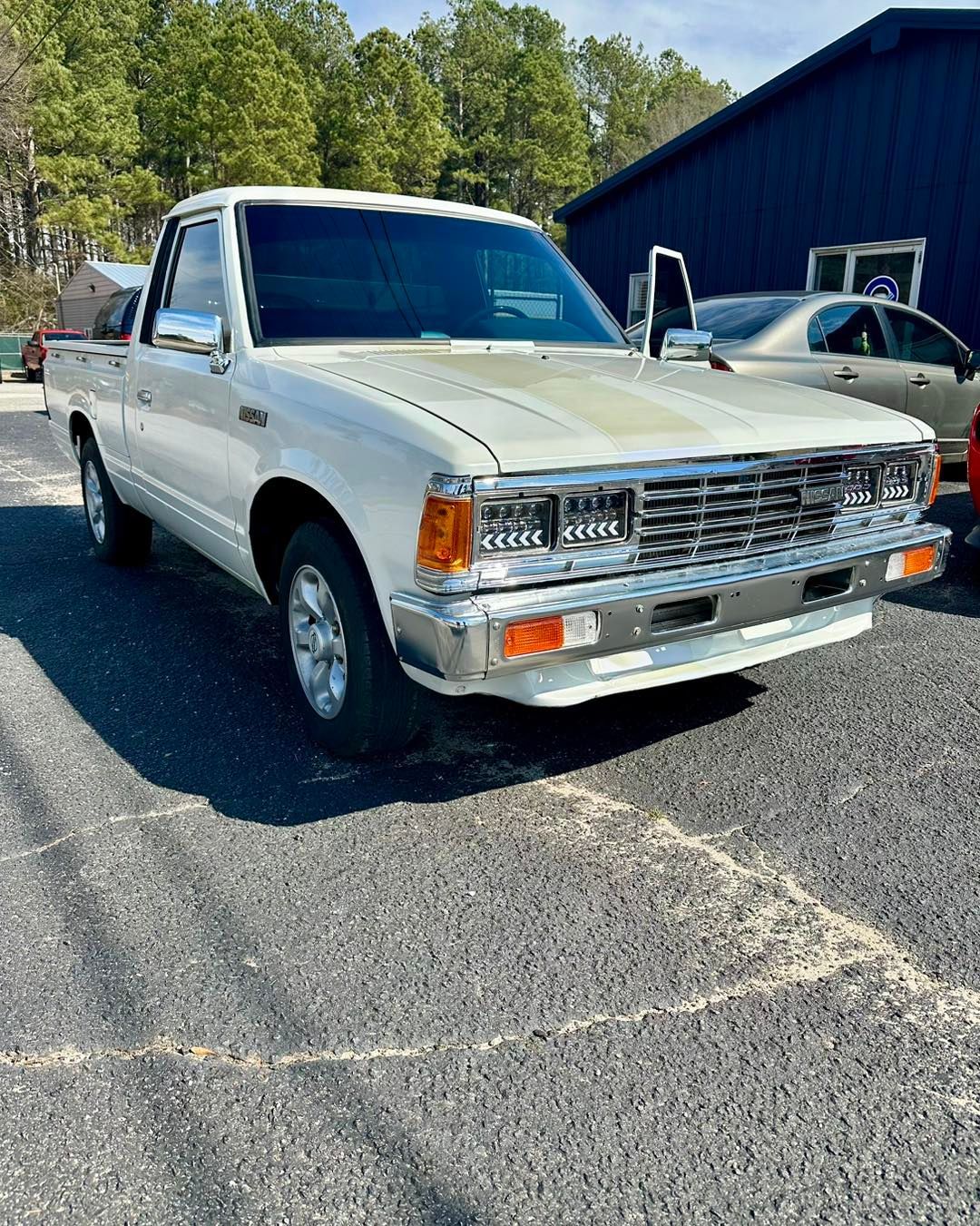 A white truck is parked in a parking lot in front of a building.