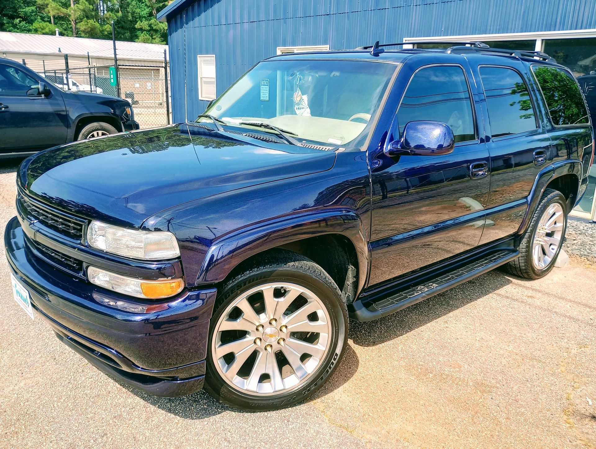 A blue suv is parked in front of a blue building.