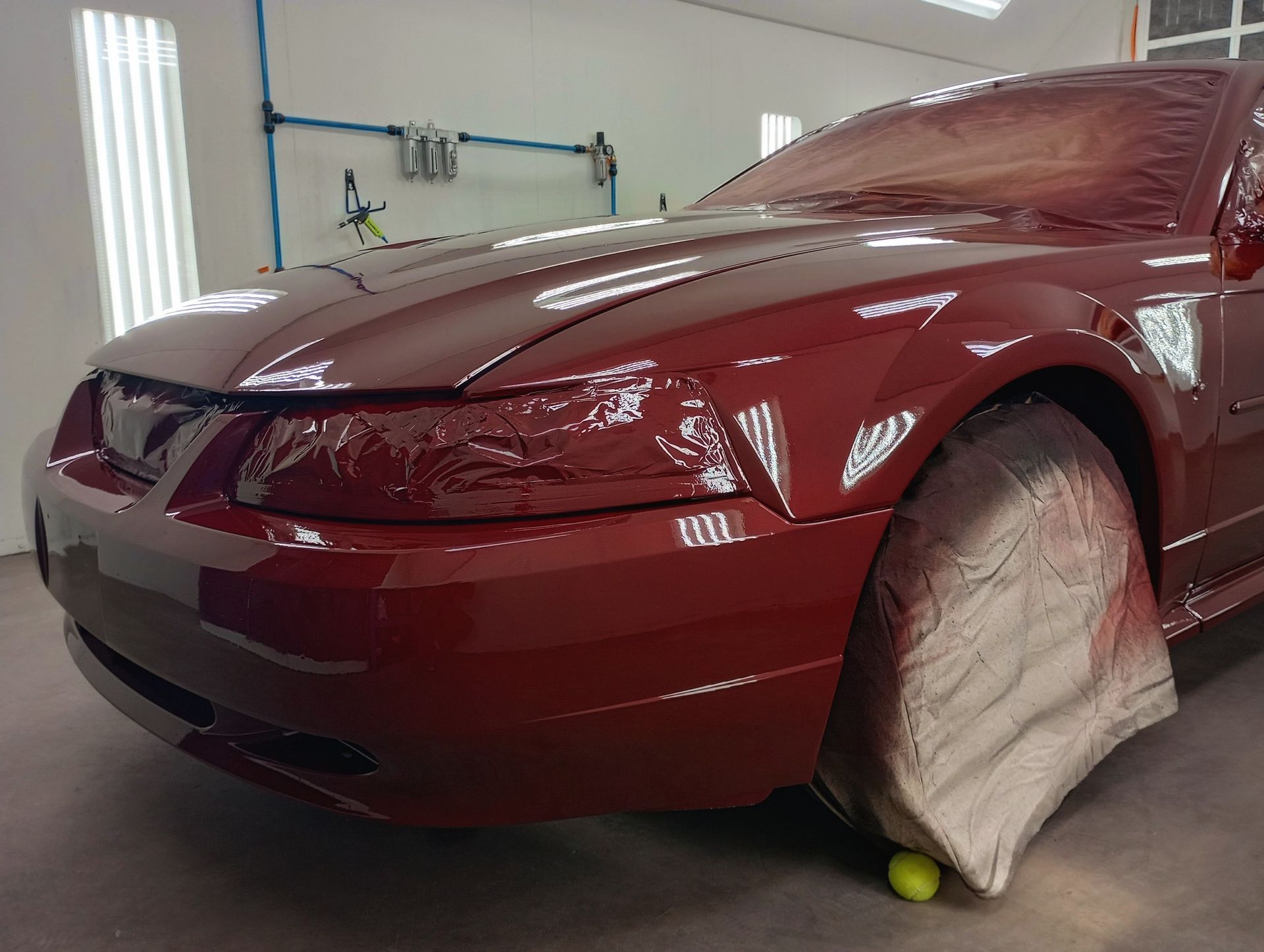 A red mustang is being painted in a garage