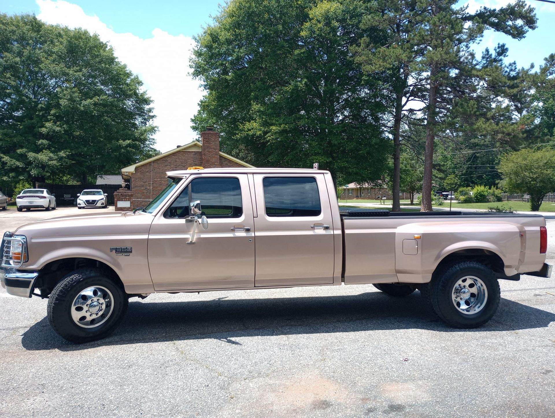 A tan pickup truck is parked in a parking lot in front of a house.
