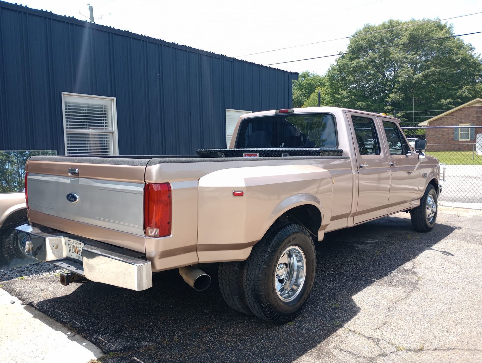 A gold ford truck is parked in front of a building.
