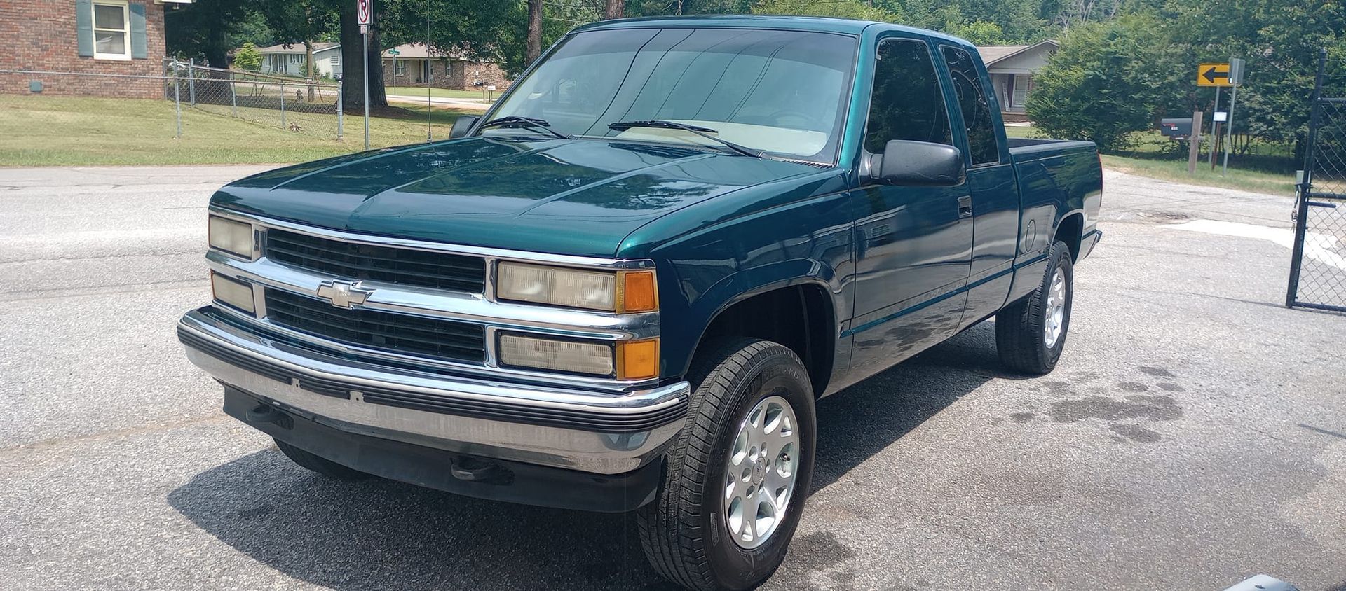 A green pickup truck is parked on the side of the road.