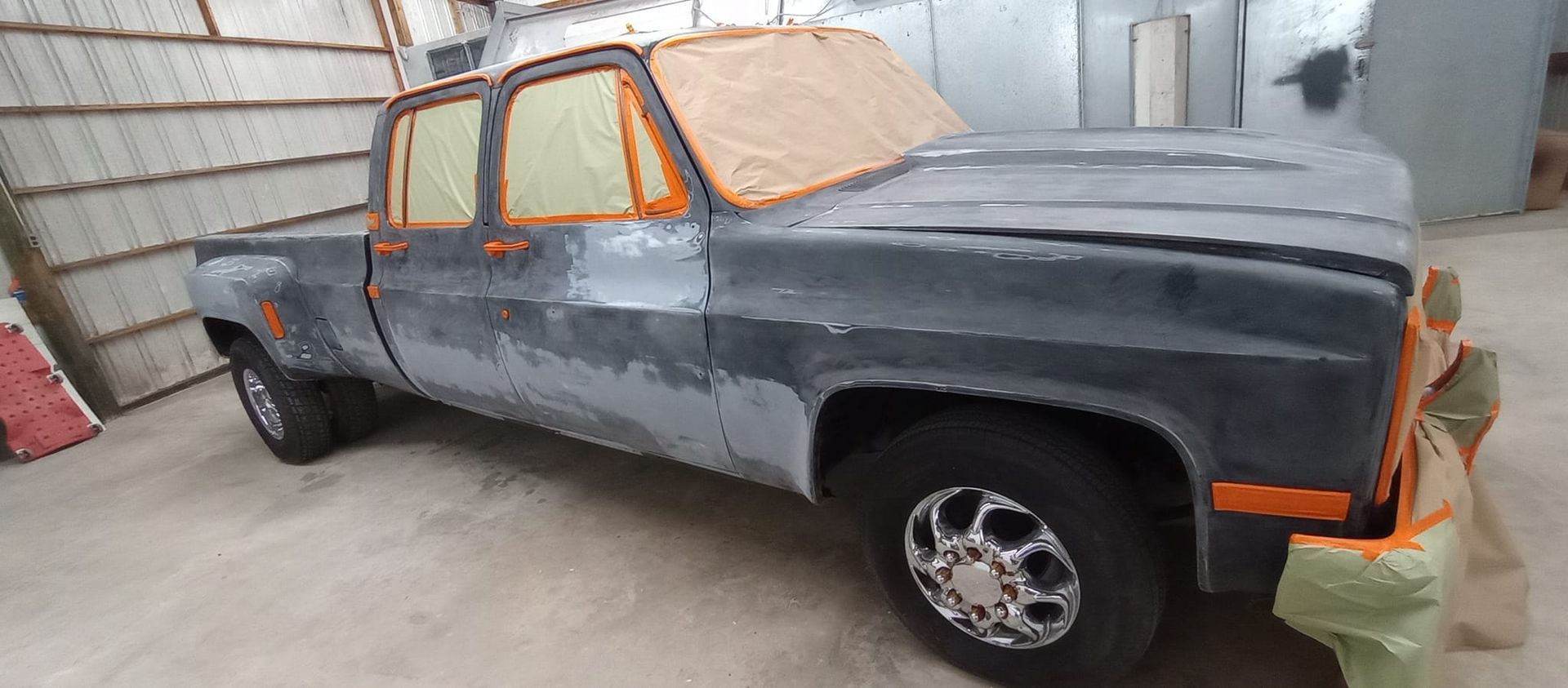 A truck is sitting in a garage being painted.