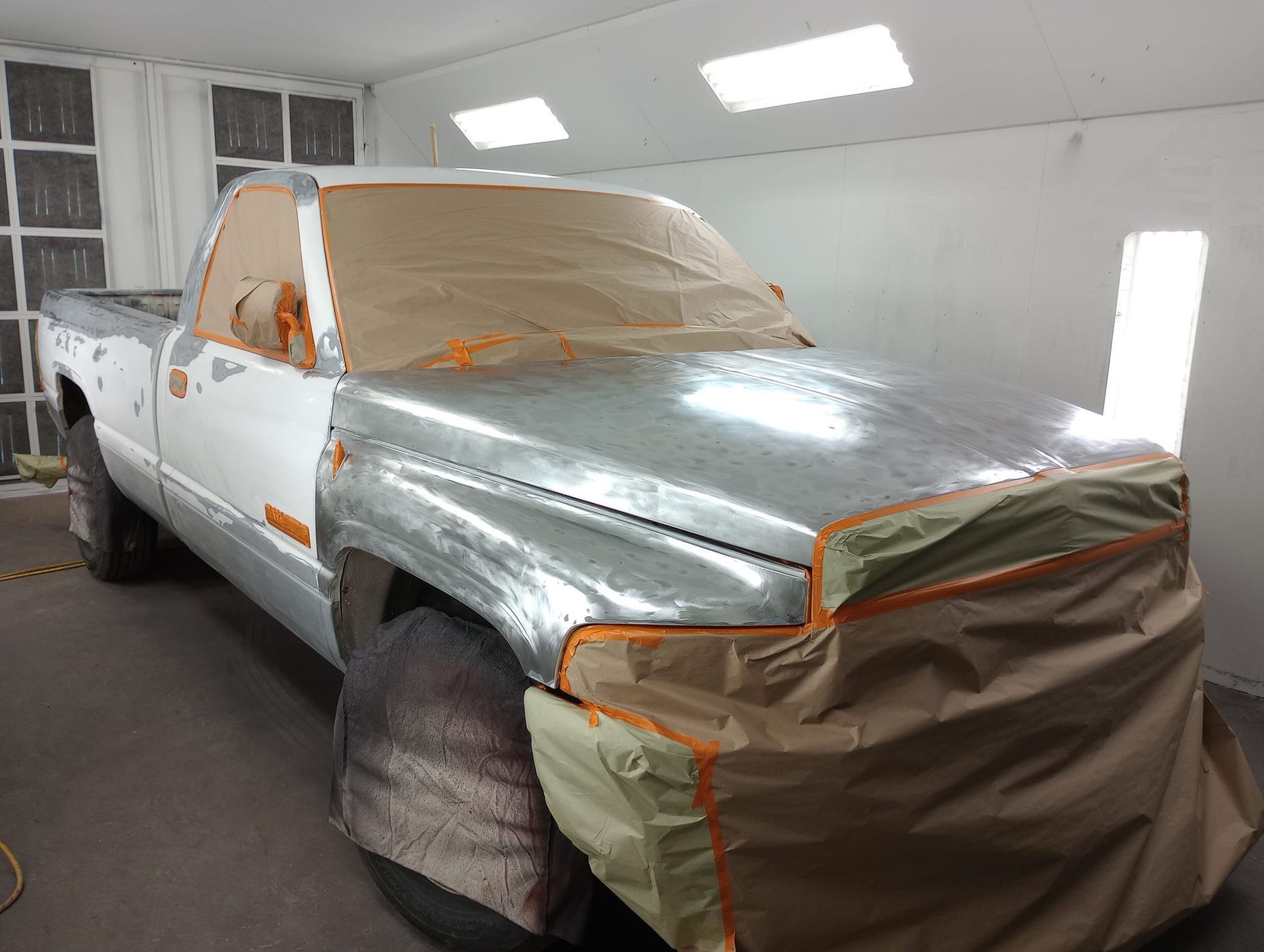 A truck is being painted in a paint booth.