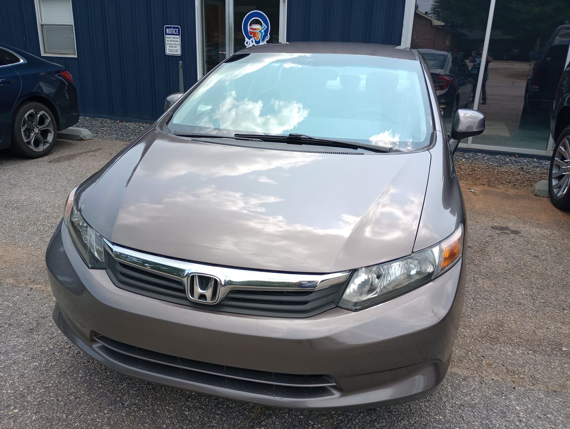 A brown honda civic is parked in front of a building.